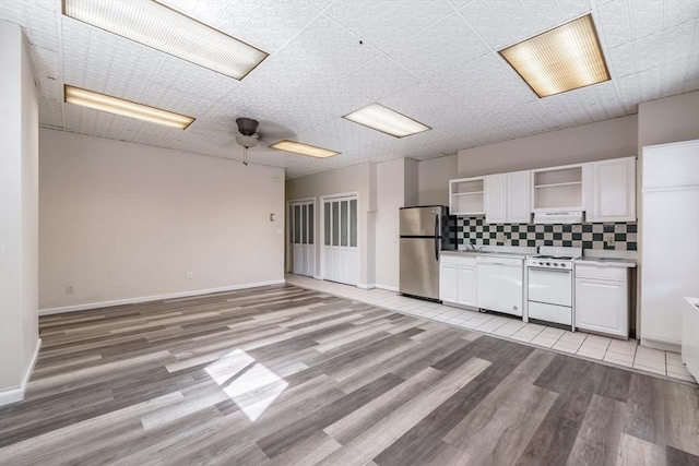 kitchen with light wood-type flooring, open shelves, white appliances, white cabinets, and decorative backsplash