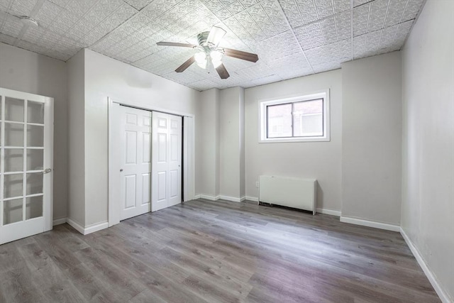 unfurnished bedroom with a closet, ceiling fan, baseboards, and wood finished floors