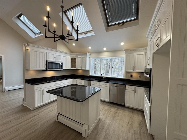 kitchen with a baseboard heating unit, hanging light fixtures, white cabinetry, and appliances with stainless steel finishes