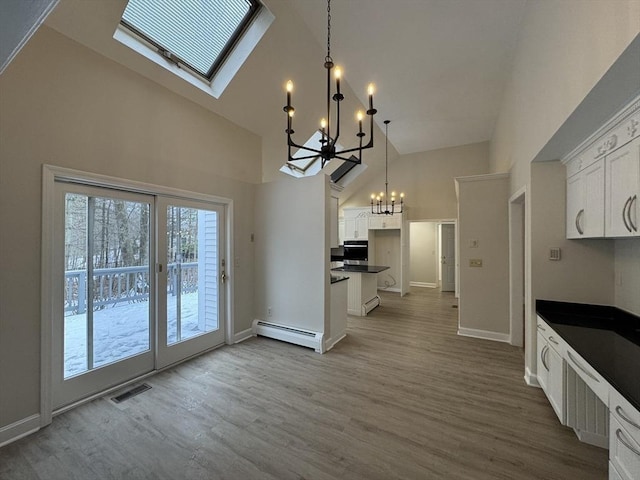 kitchen with high vaulted ceiling, decorative light fixtures, white cabinetry, a chandelier, and a baseboard heating unit