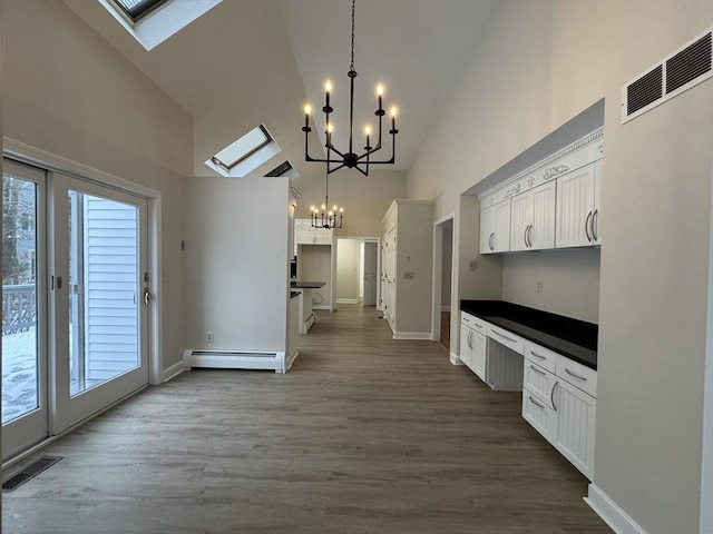 kitchen featuring high vaulted ceiling, white cabinetry, hanging light fixtures, baseboard heating, and an inviting chandelier