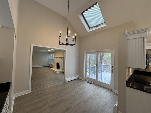 dining room featuring an inviting chandelier, hardwood / wood-style flooring, a skylight, and baseboard heating