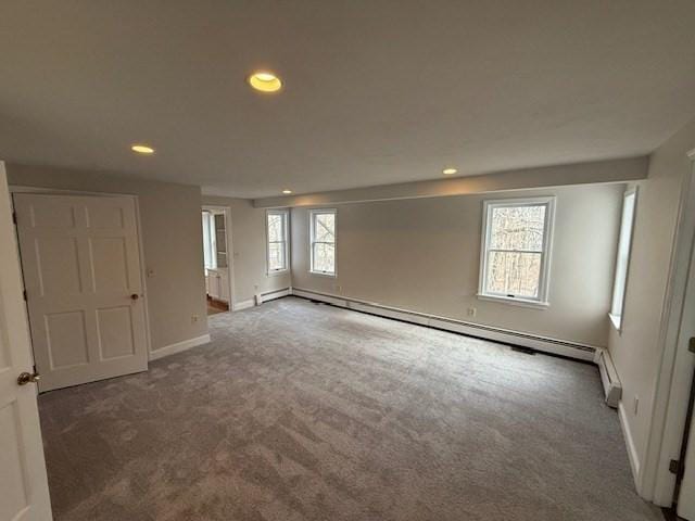 carpeted empty room with a baseboard heating unit