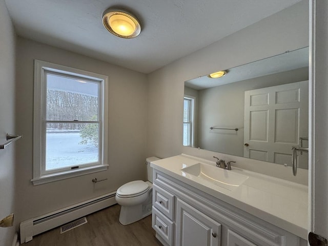 bathroom with hardwood / wood-style flooring, vanity, a baseboard heating unit, and toilet