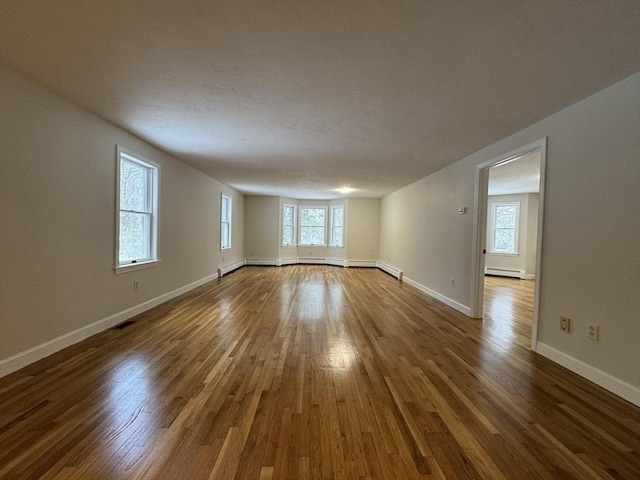 empty room featuring hardwood / wood-style floors and a baseboard heating unit