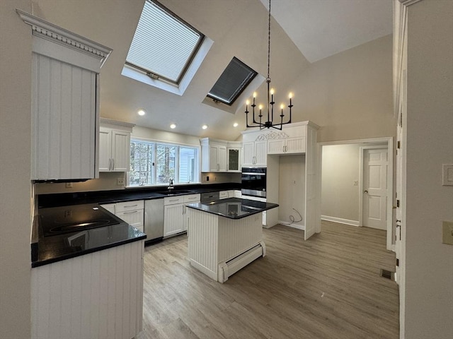 kitchen featuring sink, white cabinetry, stainless steel appliances, a kitchen island, and decorative light fixtures