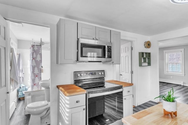 kitchen featuring stainless steel appliances, dark wood-type flooring, and wood counters