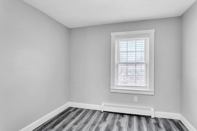 empty room featuring a baseboard heating unit and hardwood / wood-style floors