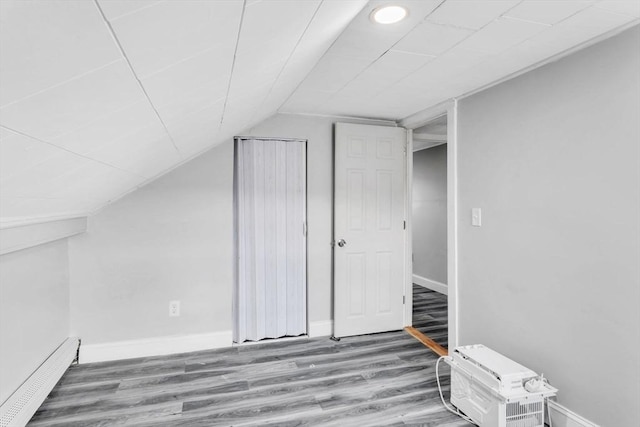 bonus room with vaulted ceiling, a baseboard radiator, and hardwood / wood-style flooring