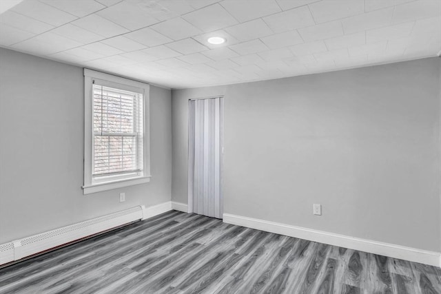 empty room featuring baseboard heating and hardwood / wood-style floors