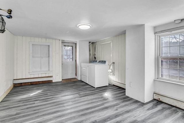 laundry area featuring washer and dryer, wood-type flooring, wood walls, and baseboard heating