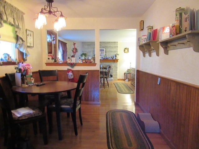 dining area with a notable chandelier, wood walls, and hardwood / wood-style flooring