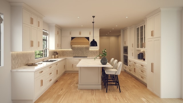 kitchen with custom range hood, decorative light fixtures, appliances with stainless steel finishes, sink, and a center island with sink