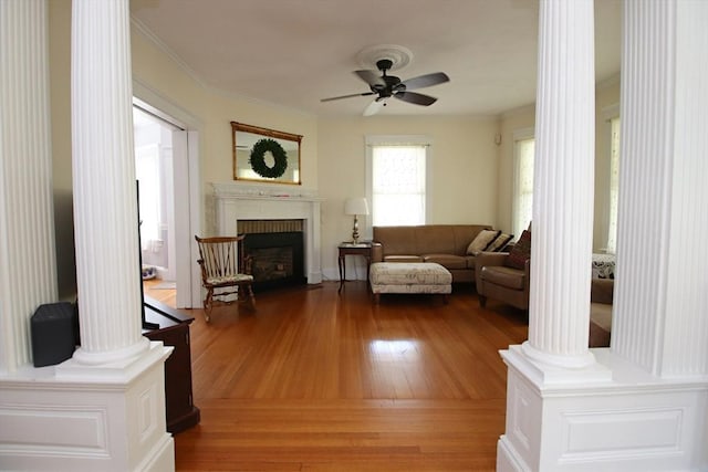 27 Summer St, Saugus, MA 01906 - living room featuring a ceiling fan, decorative columns, light wood-type flooring, a fireplace with flush hearth, and ornamental molding