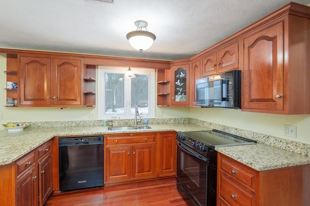 kitchen featuring dark wood-style floors, open shelves, a sink, light stone countertops, and black appliances