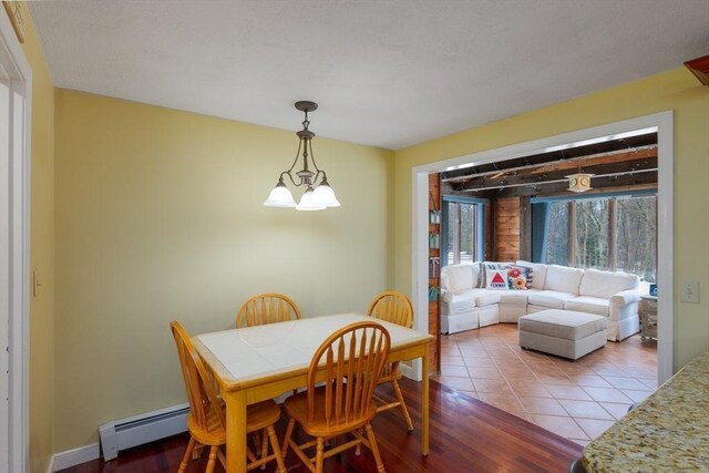 dining area featuring tile patterned flooring, a baseboard heating unit, and a chandelier