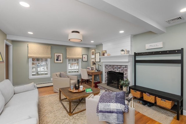 living room with a brick fireplace, visible vents, wood finished floors, and recessed lighting