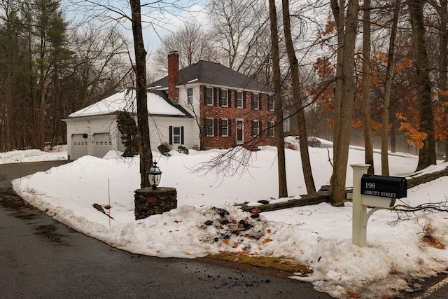 view of front of house featuring a garage, a chimney, and brick siding