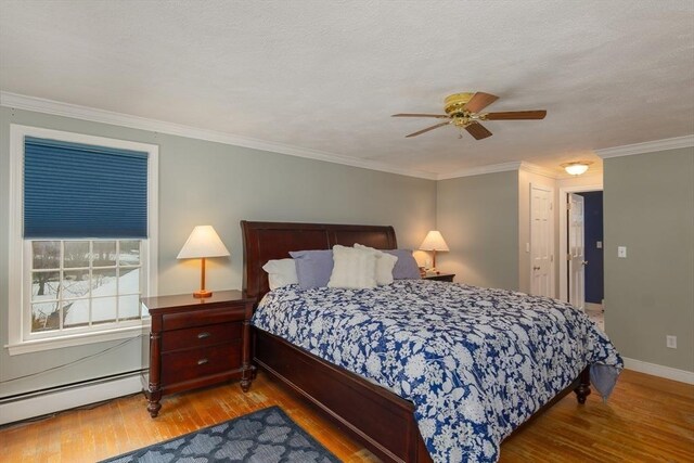 bedroom with light wood-type flooring, baseboards, ornamental molding, and baseboard heating