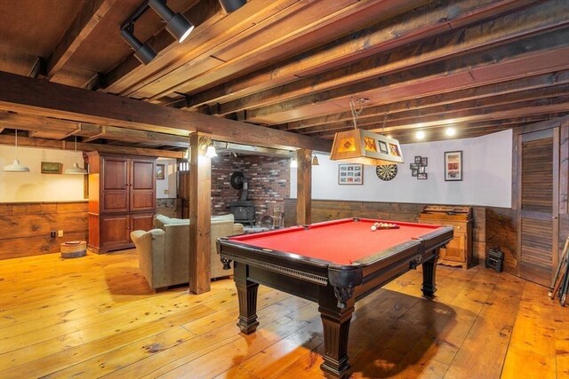 game room featuring light wood-style floors, pool table, a wood stove, and wainscoting