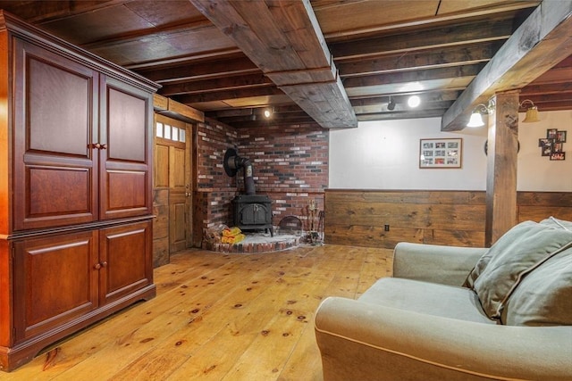 living room with a wood stove, a wainscoted wall, light wood-type flooring, and wood walls