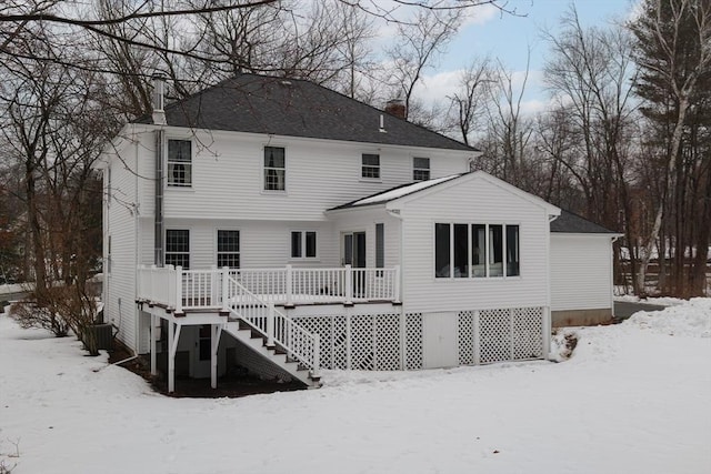 snow covered back of property featuring stairway, a chimney, and a wooden deck