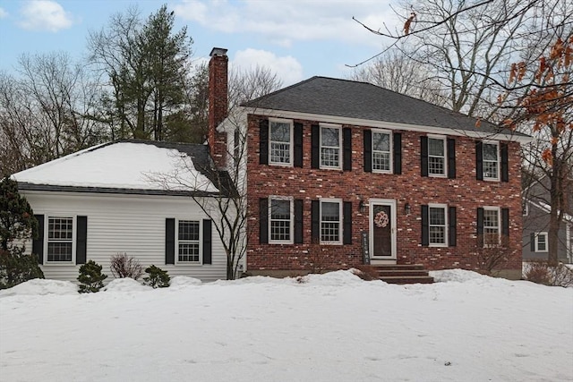 colonial home featuring brick siding and a chimney