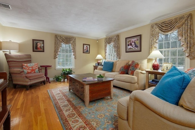 living area with plenty of natural light, wood finished floors, visible vents, and crown molding