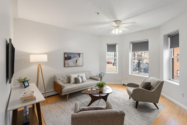 living room featuring baseboard heating, ceiling fan, and light hardwood / wood-style flooring