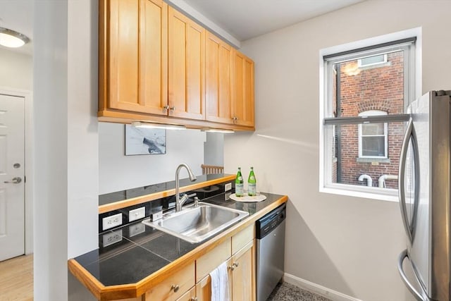 kitchen with appliances with stainless steel finishes, tile counters, light brown cabinetry, and sink