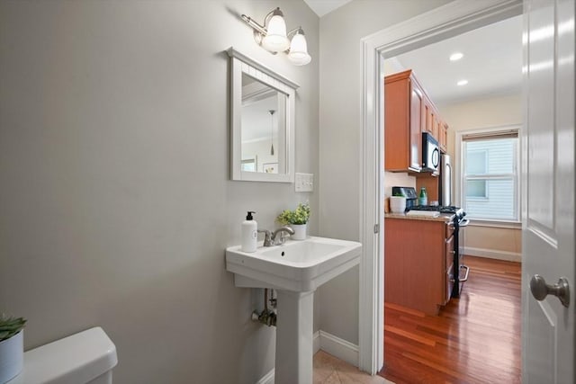297 Cardinal Medeiros Ave Unit 1, Cambridge, MA 02141 - bathroom featuring baseboards, toilet, wood finished floors, recessed lighting, and a sink