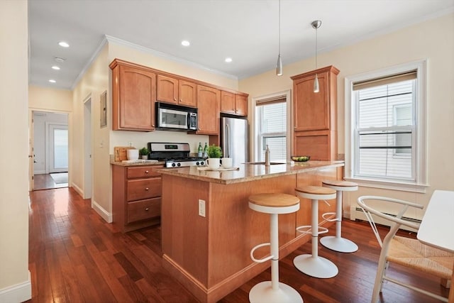 297 Cardinal Medeiros Ave Unit 1, Cambridge, MA 02141 - kitchen with stainless steel appliances, baseboard heating, crown molding, dark wood-type flooring, and a kitchen breakfast bar
