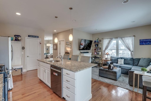 kitchen with white cabinets, sink, hanging light fixtures, light stone countertops, and appliances with stainless steel finishes