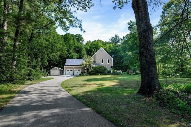61 Northbridge Rd, Mendon, MA 01756 - view of front facade with driveway, a front lawn, roof mounted solar panels, a garage, and a wooded view