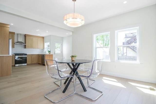 dining area with baseboards, plenty of natural light, and light wood-style floors