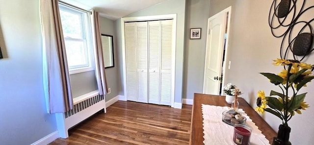 hall featuring radiator heating unit, baseboards, lofted ceiling, and wood finished floors