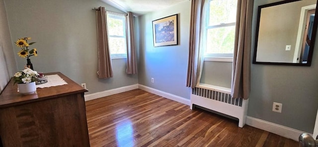 empty room with radiator, baseboards, dark wood-style flooring, and lofted ceiling