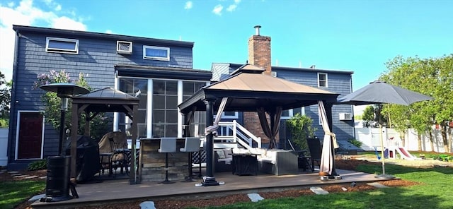rear view of house featuring a gazebo, a chimney, a sunroom, and a patio area