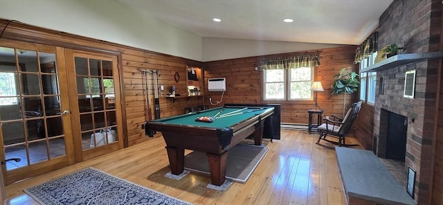 rec room featuring lofted ceiling, light wood finished floors, billiards, wood walls, and a fireplace