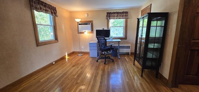 office area with wood finished floors, radiator, a wall mounted AC, and baseboards