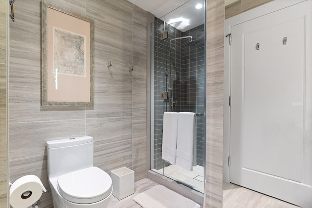 bathroom with tile walls, a shower with shower door, and toilet