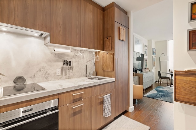 kitchen with light stone countertops, dark hardwood / wood-style floors, tasteful backsplash, oven, and sink