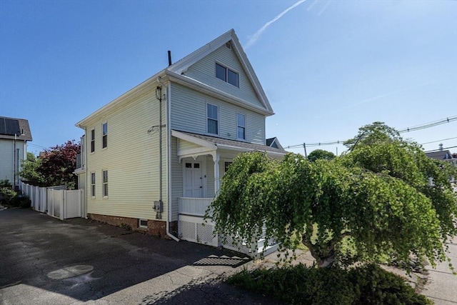 american foursquare style home featuring a porch and fence