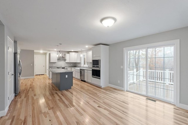 kitchen with appliances with stainless steel finishes, wall chimney range hood, baseboards, and recessed lighting