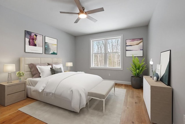 bedroom with light wood-style flooring, baseboards, and a ceiling fan