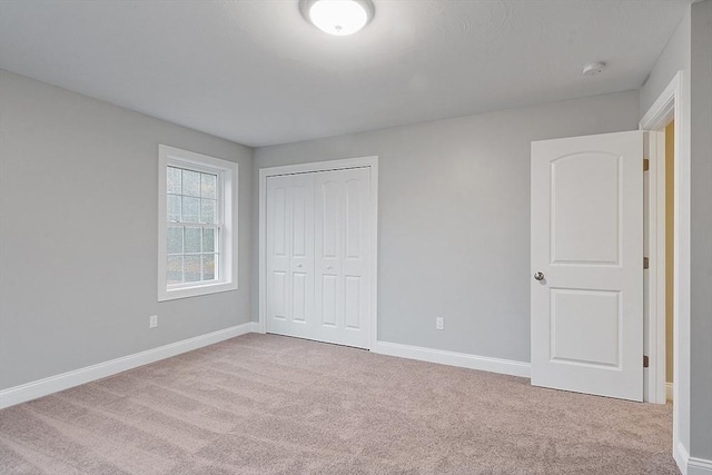 unfurnished bedroom featuring carpet floors, baseboards, and a closet
