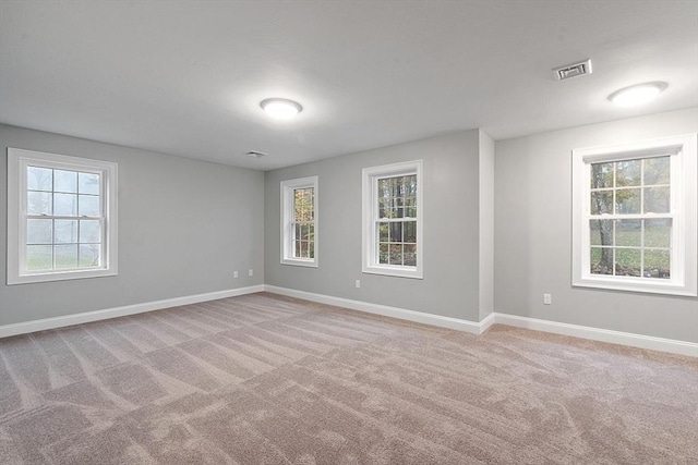 empty room with baseboards, plenty of natural light, and light colored carpet