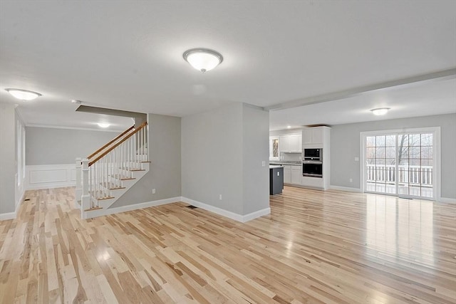 unfurnished living room with light wood-type flooring, stairs, and baseboards