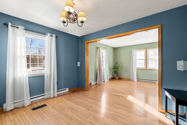 interior space with a baseboard heating unit, light hardwood / wood-style flooring, and a chandelier