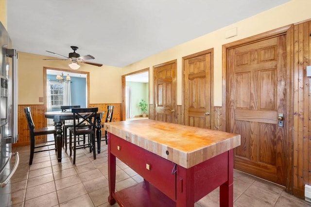 kitchen with light tile patterned flooring, wood counters, wooden walls, and ceiling fan